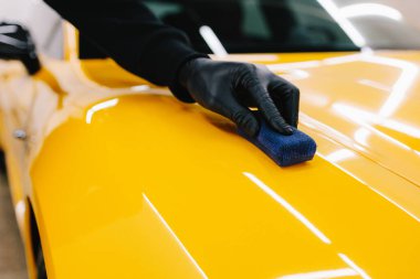 Sarı spor araba için koruyucu nano katman oluşturmak için seramik sıvıyı karıştırmak. Ayrıntılı hizmet çalışanı spor arabaya seramik koruyucu sıvı uygular