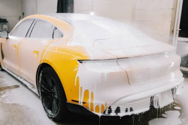 Araba yıkama yerindeki kiri ve tozu temizlerken yüksek basınçlı su tabancası sabunlu çözeltiyi aracın yüzeyine sıkarak temizler.