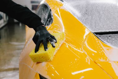 Araba servisinde temizlik için köpüklü süngerle araba yıkamak. Detaylandırmak için ayarlanmış bir araba hazırlanıyor