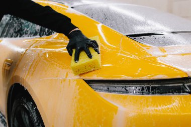 Adam sabun solüsyonu ve sünger kullanarak spor arabayı yıkar. Araba servisinde çok titiz araba detayı konsepti