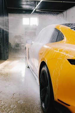 Yüksek basınçlı su tabancası detaylı temizlik için aracın yüzeyine sabun püskürtüyor. Araba yıkamada toz ve çamurdan araba temizliği.