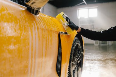 Oto yıkamada sünger ve köpük kullanarak spor arabaların el temizliği, oto yıkama işleminden önce sabun solüsyonuyla yıkama..