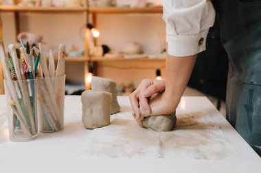 Çömlek atölyesindeki masaya seramik kil ürünü yapan bir kadın çömlekçinin elleri. Potter seramik ürünleri için ıslak kil heykeli yapıyor.