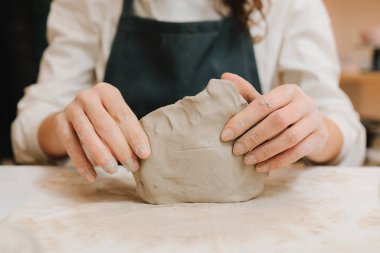 Çömlek atölyesindeki masaya seramik kil ürünü yapan bir kadın çömlekçinin elleri. Potter seramik ürünleri için ıslak kil heykeli yapıyor.