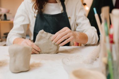 Çömlek atölyesindeki masaya seramik kil ürünü yapan bir kadın çömlekçinin elleri. Potter seramik ürünleri için ıslak kil heykeli yapıyor.