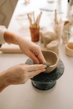 Atölyede seramik çanak çömlek yapmak. Sanatçı kadın çömlekçi çarkında kilden bir kase yapıyor.