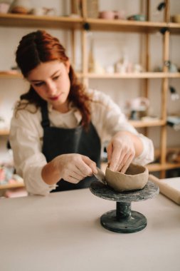 Atölyede seramik çanak çömlek yapmak. Sanatçı kadın çömlekçi çarkında kilden bir kase yapıyor.