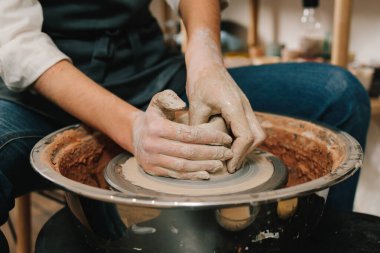 Çömlek atölyesindeki dönen çarkın üzerinde seramik toprak malzemesi yapma süreci. Zanaatkar çömlek çarkına ıslak bir kil kalıbı koyar.