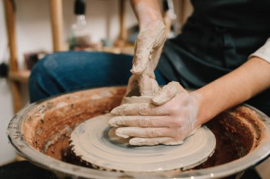 Potter çömlek atölyesinde kilden seramik bir kupa yontuyor. Çömlekçi araçlarıyla toprak kalıbı oluşturuluyor