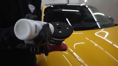 4K videosu olan profesyonel araba. Usta, araba gövdesini cilalamak için göz çukuru makinesine mum yapıştırıcı sürer.