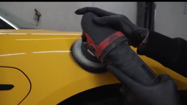 Yörüngesel cilalama ile cilalamak için aşındırıcı macun kullanmak 4k 'lık çizik videosunu silmek için. Araba servisindeki yörünge cilası makinesini kullanarak sarı spor araba kaput yüzeyinin cilalanması süreci ayrıntılandırılıyor