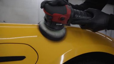 Yörüngesel cilalama ile cilalamak için aşındırıcı macun kullanmak 4k 'lık çizik videosunu silmek için. Araba servisindeki yörünge cilası makinesini kullanarak sarı spor araba kaput yüzeyinin cilalanması süreci ayrıntılandırılıyor