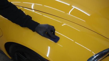 Detaylı servis çalışanı spor arabaya seramik koruma sıvısı uygular. Sarı spor araba 4K video için koruyucu nano katman oluşturmak için seramik sıvıyı karalamak.