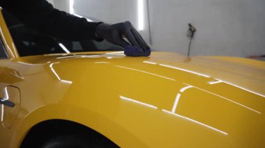 Sarı spor araba 4K videosu için seramik sıvıyı sürerek koruyucu nano katman oluşturuyor. Ayrıntılı hizmet çalışanı spor arabaya seramik koruyucu sıvı uygular