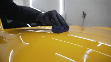 Sarı spor araba 4K videosu için seramik sıvıyı sürerek koruyucu nano katman oluşturuyor. Ayrıntılı hizmet çalışanı spor arabaya seramik koruyucu sıvı uygular