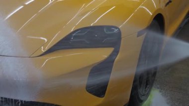 Servis videosunda spor araba temizliği için sabunlu köpük ve su tabancası uygulaması. İşçi sabun solüsyonunu araba yıkama için su jeti basıncıyla spreyliyor