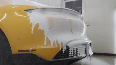 Garaj videosundaki cesede köpük püskürtme işlemi. Araba servisinde yıkamanın ikinci aşaması. Araba yıkama makinesi tüm oto yıkamayı yapar.