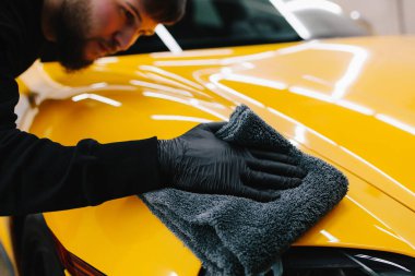Oto servisinde mikrofiberle kurutulan el arabası. Araba yıkadıktan sonra temizlikçi kuru araba.
