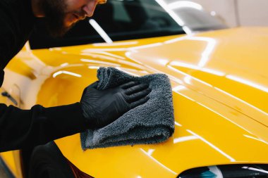 Temizlikçi, araba yıkadıktan sonra mikro fiber kullanıyor. Otomobil servisinde mikrofiberle kurutulan el arabası.