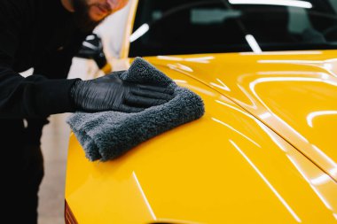Oto servisinde mikrofiberle kurutulan el arabası. Araba yıkadıktan sonra temizlikçi kuru araba.