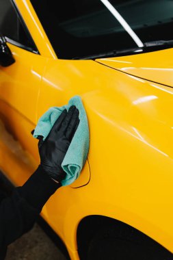 Mikro fiber silme, araba silme, cilalama ve valelik gibi titiz detaylar. Adam araba servisinde prosedürü detaylandırmadan önce arabayı mikrofiber bezle cilalıyor.