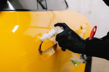 Araba tutacağı mikrofiber ve deterjan ile oto yıkama servisinde. Temizlikçi, araba yıkadıktan sonra araba sapını fırçalıyor.