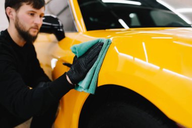 Adam araba servisinde prosedürü detaylandırmadan önce arabayı mikrofiber bezle cilalıyor. Araba cilalama ve valeliğin titiz detaylandırılması