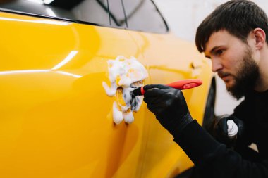 Araba tutacağı mikrofiber ve deterjan ile oto yıkama servisinde. Temizlikçi, araba yıkadıktan sonra araba sapını fırçalıyor.