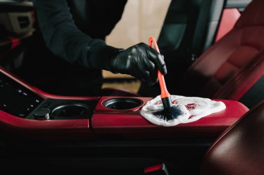 Araba yıkatma işlemi araba yıkamada sabun köpüğüyle temizleniyor. Adam arabanın kırmızı derisine köpük sürüp temizler.