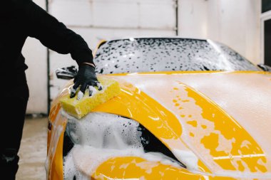 Araba servisinde temizlik için köpüklü süngerle araba yıkamak. Detaylandırmak için ayarlanmış bir araba hazırlanıyor