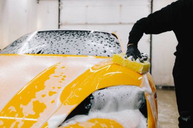 Adam sabun solüsyonu ve sünger kullanarak spor arabayı yıkar. Araba servisinde çok titiz araba detayı konsepti