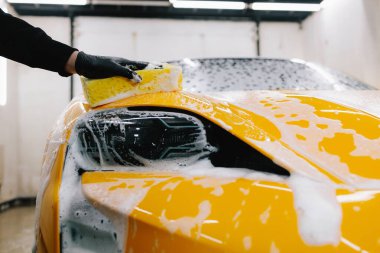 Araba servisinde temizlik için köpüklü süngerle araba yıkamak. Detaylandırmak için ayarlanmış bir araba hazırlanıyor