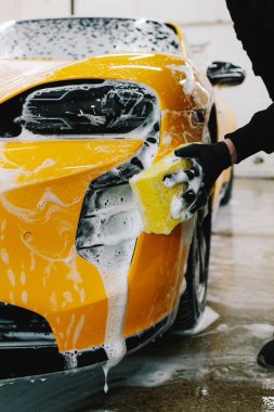Araba servisinde temizlik için köpüklü süngerle araba yıkamak. Detaylandırmak için ayarlanmış bir araba hazırlanıyor