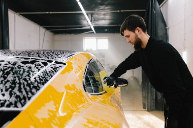 Araba servisinde temizlik için köpüklü süngerle araba yıkamak. Detaylandırmak için ayarlanmış bir araba hazırlanıyor