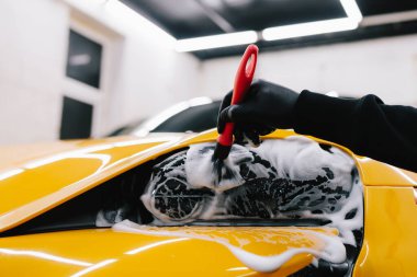 Araba farlarını köpük ve yumuşak fırçayla temizliyorum. Spor araba farlarını temizleme işlemi. Sabun köpüğü ve fırçayla yıkayın.