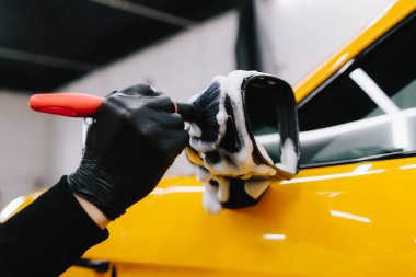 Arabanın aynasına sabunlu bir solüsyon sürme prosedürünü fırça kullanarak detaylandırıyorum. Oto yıkamada çok titiz bir araba.