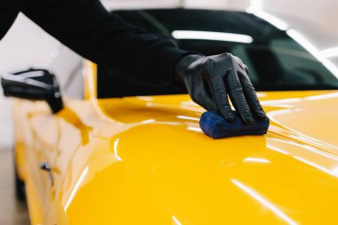 Sarı spor araba için koruyucu nano katman oluşturmak için seramik sıvıyı karıştırmak. Ayrıntılı hizmet çalışanı spor arabaya seramik koruyucu sıvı uygular