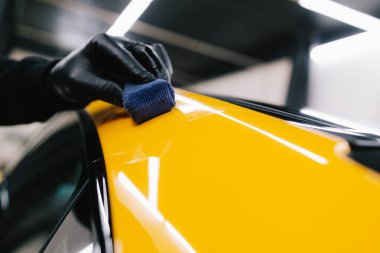 Araba servisi çalışanı spor araba gövdesine seramik kaplama uyguluyor. Detaylandırma servisinde seramik kaplama prosedürü.