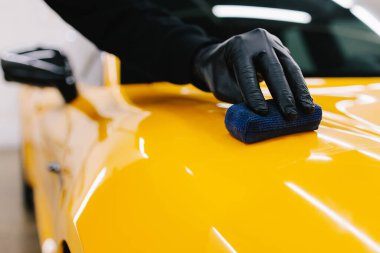 Sarı spor araba için koruyucu nano katman oluşturmak için seramik sıvıyı karıştırmak. Ayrıntılı hizmet çalışanı spor arabaya seramik koruyucu sıvı uygular