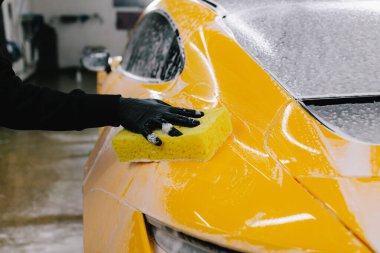 Araba servisinde temizlik için köpüklü süngerle araba yıkamak. Detaylandırmak için ayarlanmış bir araba hazırlanıyor