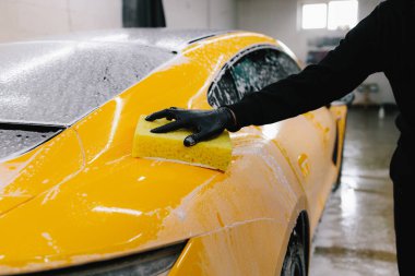 Araba servisinde temizlik için köpüklü süngerle araba yıkamak. Detaylandırmak için ayarlanmış bir araba hazırlanıyor