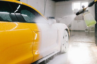Garajdaki araba cesedine köpük püskürtme işlemi. Araba servisinde yıkamanın ikinci aşaması. Araba yıkama makinesi tüm oto yıkamayı yapar.