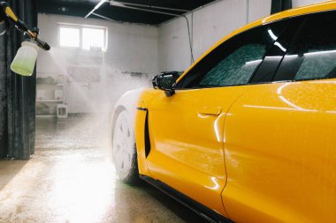 Garajdaki araba cesedine köpük püskürtme işlemi. Araba servisinde yıkamanın ikinci aşaması. Araba yıkama makinesi tüm oto yıkamayı yapar.
