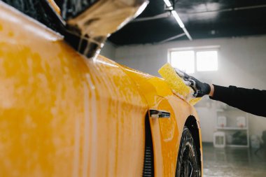 Oto yıkamada sünger ve köpük kullanarak spor arabaların el temizliği, oto yıkama işleminden önce sabun solüsyonuyla yıkama..