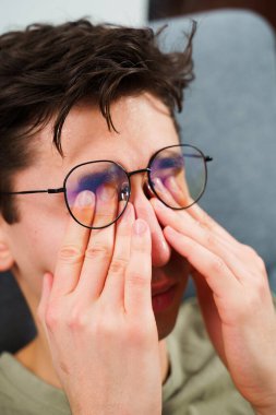 Evde uzaktan çalışmaktan göz yorgunluğu. Dizüstü bilgisayarın önünde baş ağrısı çeken yorgun bir bilişim uzmanı.