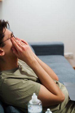 Bilgisayarla çalıştıktan sonra görme sorunu yaşıyor. Yorgun adam dizüstü bilgisayarla çalıştıktan sonra gözlerine masaj yapıyor.