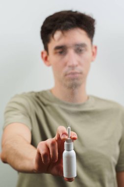 Burun spreyi beyaz şişesi insanların elinde. Evde sinüzit ve eczane tedavisi düşüyor.