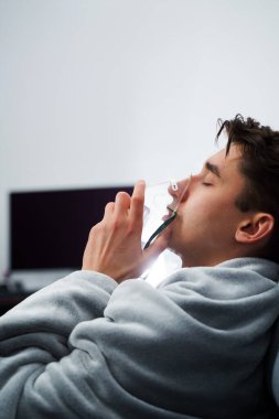 Evde öksürük tedavisi için nebulizör maskesiyle hava solumak. Hasta adam nebulizatörle solunum tedavisi görüyor.