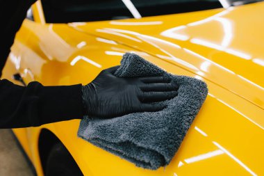 Temizlikçi, araba yıkadıktan sonra mikro fiber kullanıyor. Otomobil servisinde mikrofiberle kurutulan el arabası.