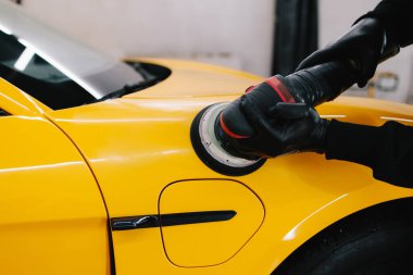 Spor arabayı cilalamak, çizikleri silmek için aşındırıcı macunla cilalamak. Tamir atölyesinde araba cilası cilalayan araba tamircisinin elleri.